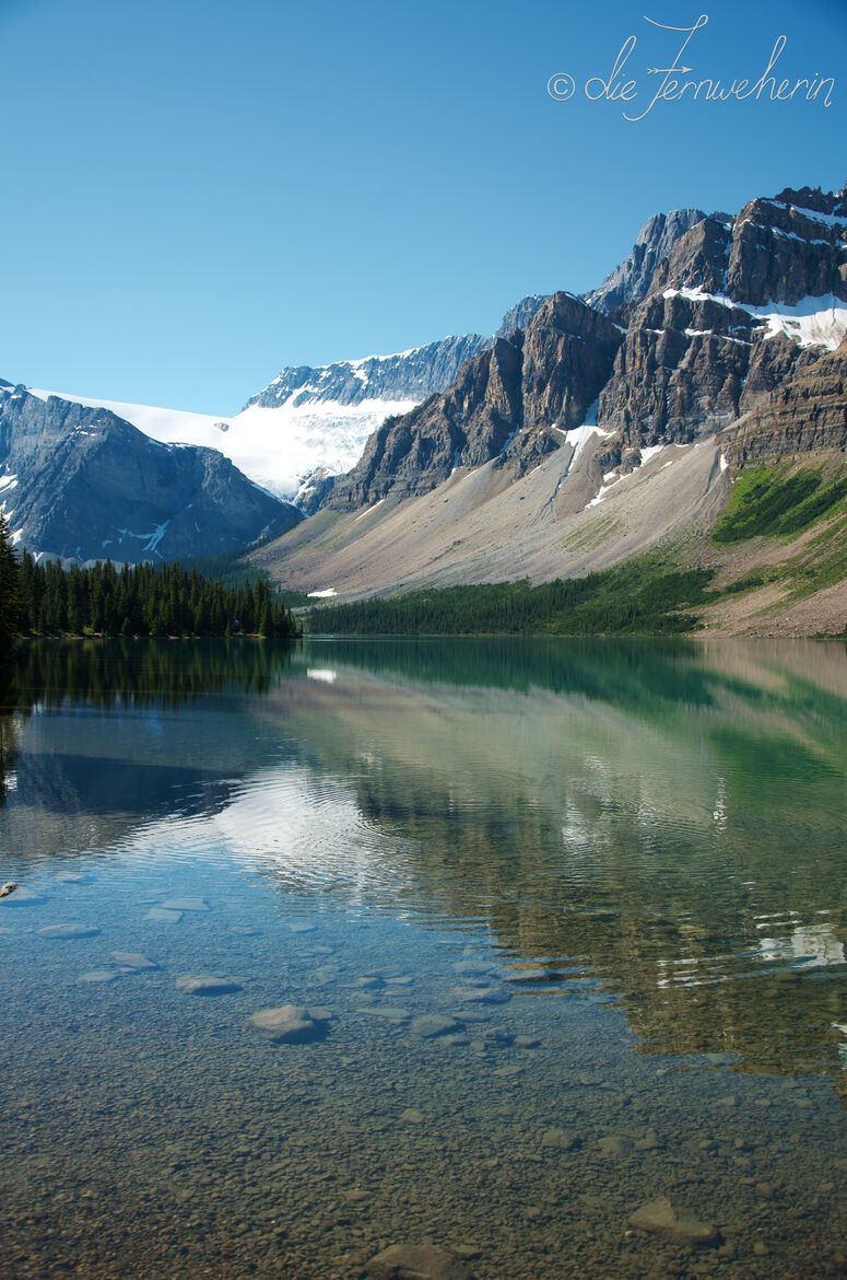 Bow Glacier and the surrounding mountains are reflected in crystal-clear Bow Lake along the Icefields Parkway in Banff National Park.