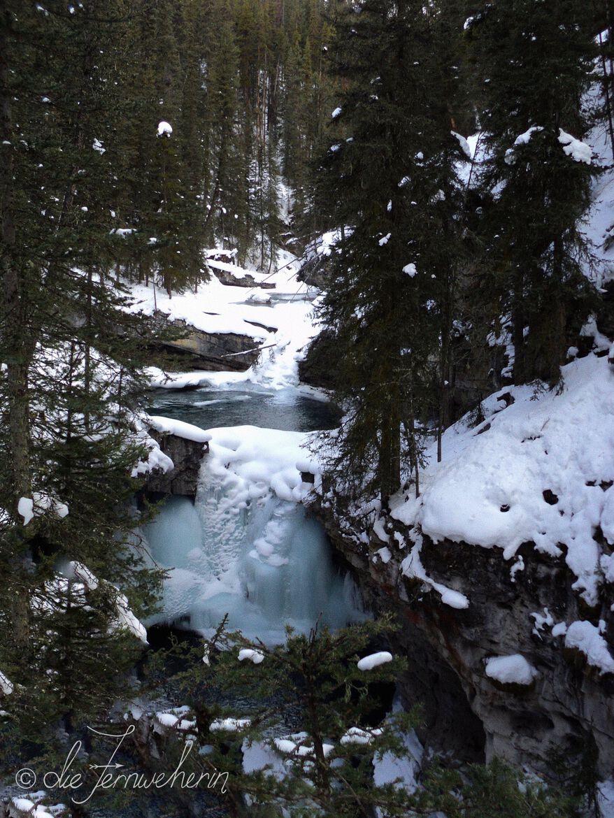A partially-frozen miniature waterfall in Banff National Park's Johnston Canyon in winter.