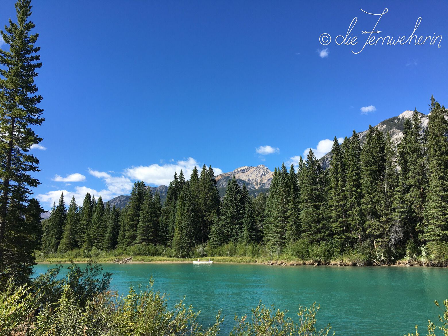 A canoe docks on the opposite side of the beautiful blue Bow River, as seen from the Sundance Trail in the town of Banff.