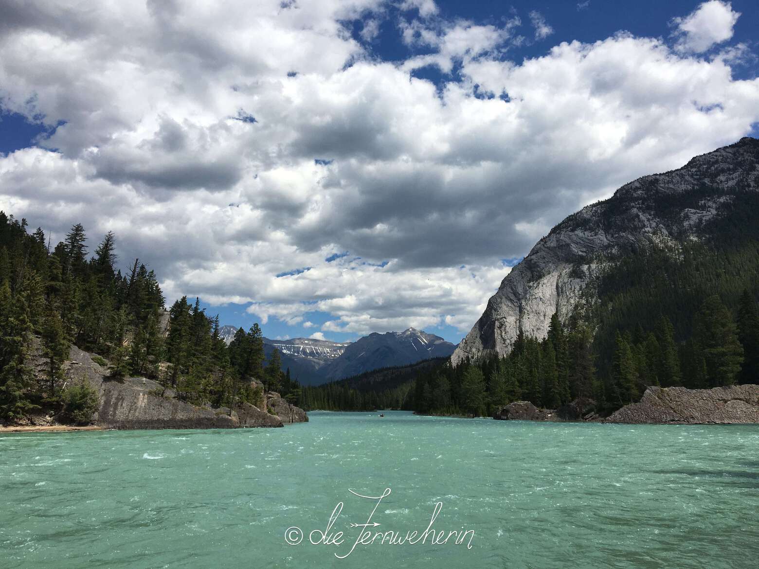 A canoe floats between two rocky outcrops flanking ether side of the Bow River on the outskirts of the town of Banff.