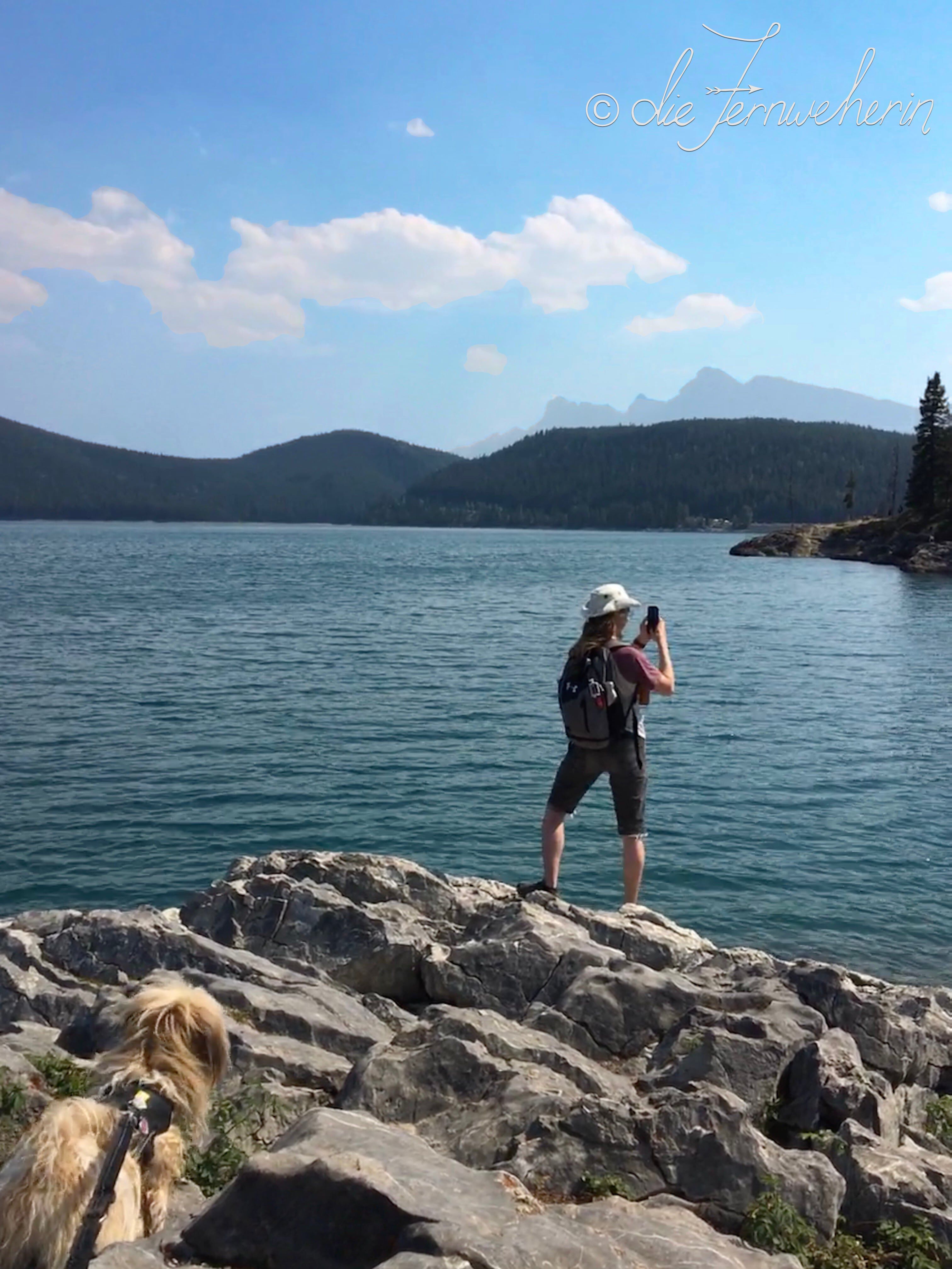 A man takes a photograph of Lake Minnewanka in Banff National Park.