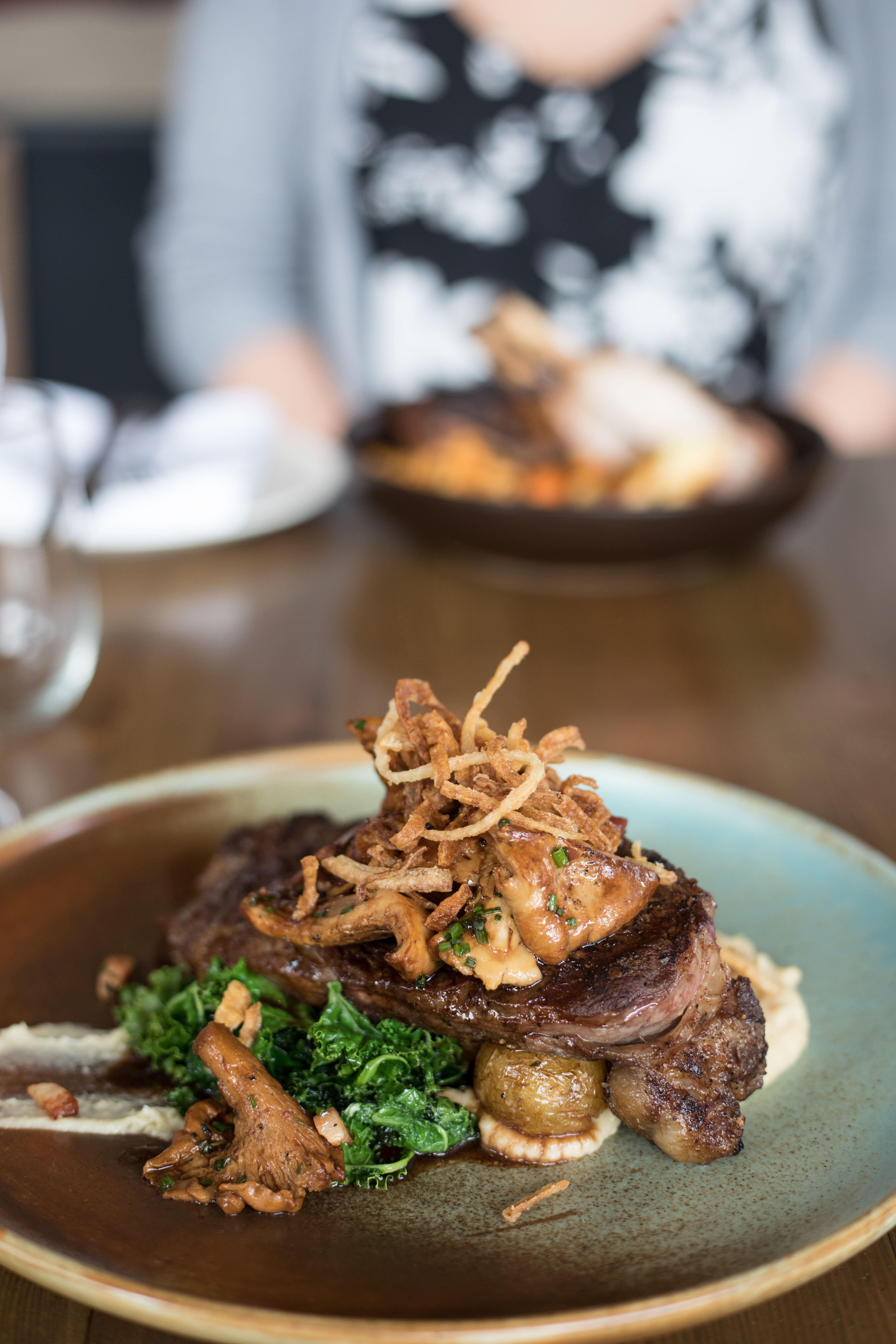 A bison steak on a bed of roasted vegetables with crispy onions on top at The Bison, a restaurant in the town of Banff.