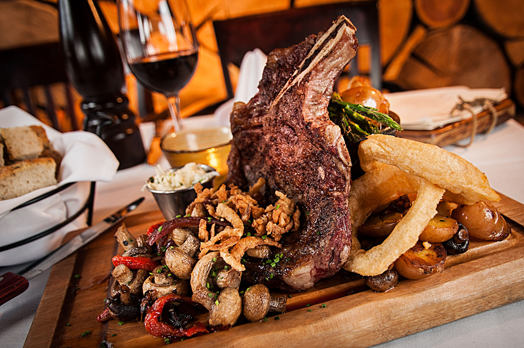 A wooden board piled high with food (ribeye steak, roasted veggies, potatoes, crispy onions) at The Maple Leaf, a restaurant in the town of Banff.
