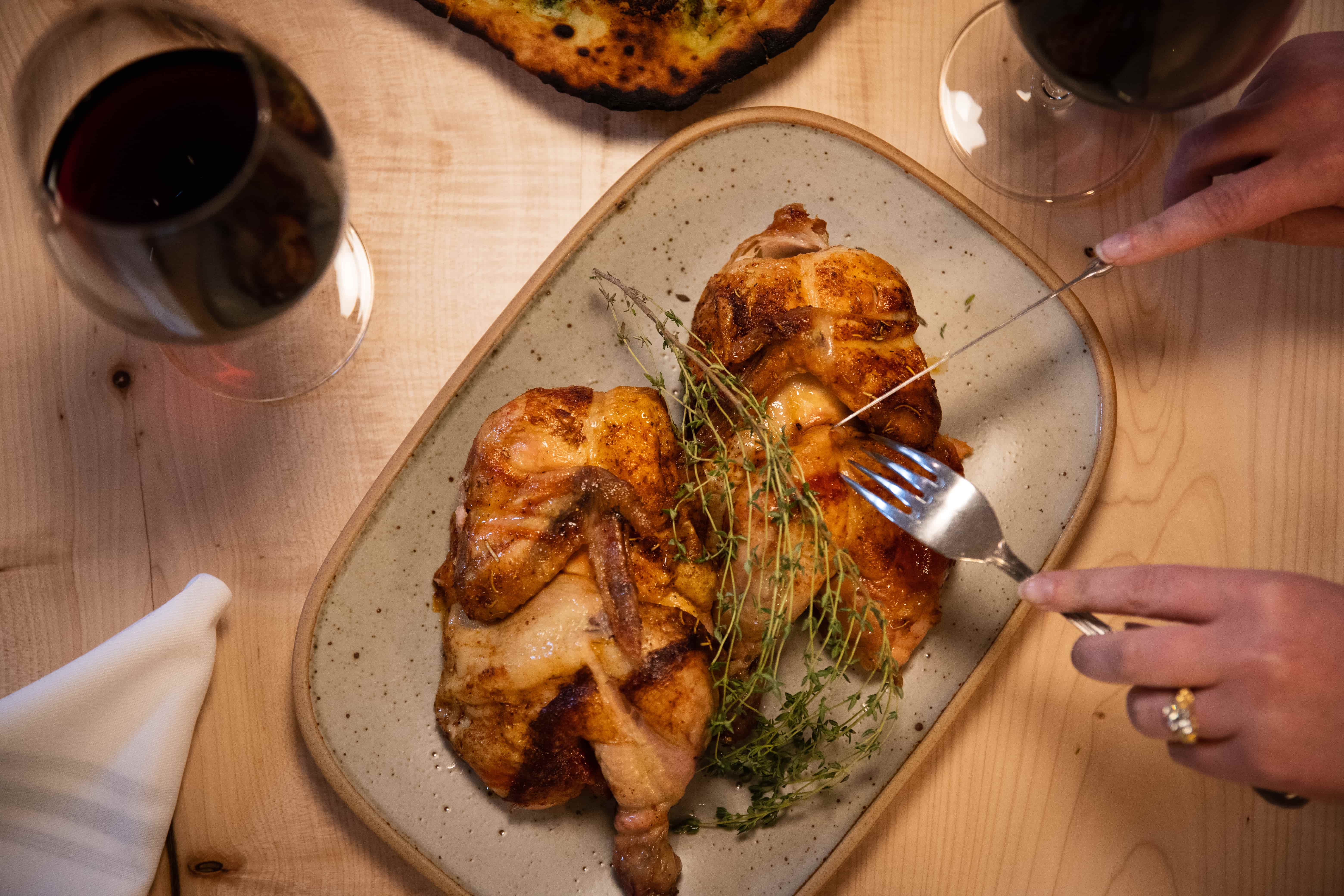 A patron digs into a plate of rotisserie chicken at Farm & Fire.