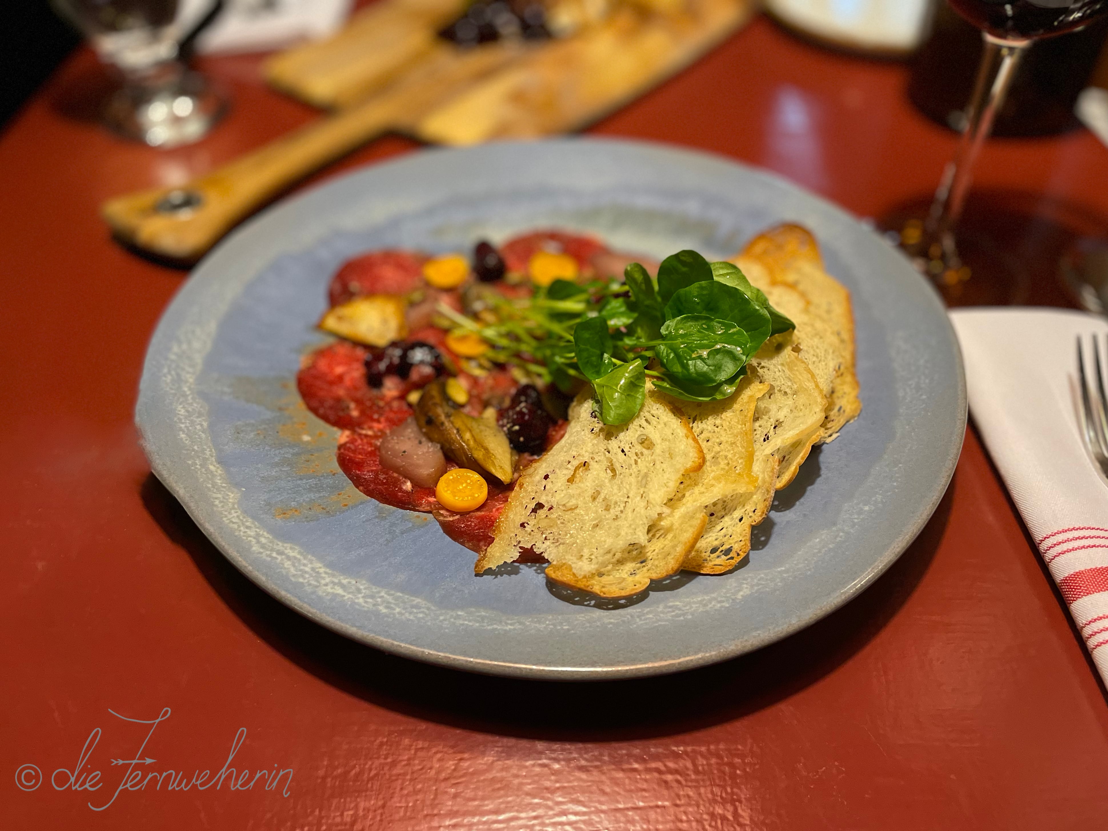The delicious Bison Carpaccio appetizer at Storm Mountain Lodge, accompanied by house-made crostini, pickled berries, capers, peppery greens, and local mushrooms.